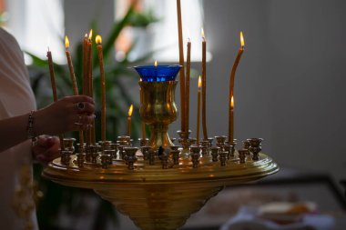 Bir kadının eli, Ortodoks kilisesinin mihrabına mum koyar..