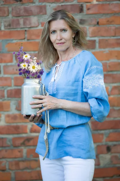 Piękna Starsza Kobieta Słowiańskim Wyglądzie Haftowanej Koszuli Trzyma Puszkę Kwiatów — Zdjęcie stockowe