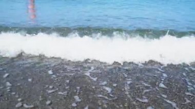 Sea wave flows over the pebbles of the beach.