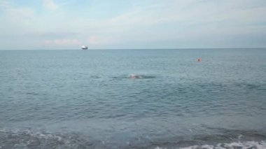 A man in a business suit emerges from the sea.