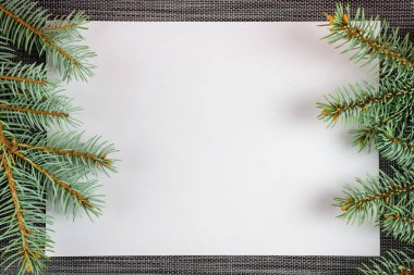 Noel ağacının dallarıyla süslenmiş beyaz bir yaprak kağıt. Yeni yıl arkaplanında bir sopi alanı var. Noel süslemesi.