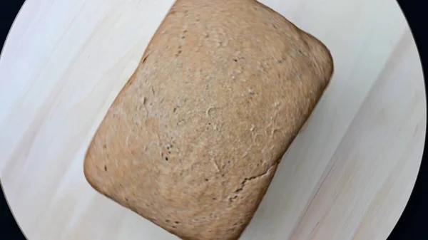 Świeżo Upieczony Chleb Żytni Obraca Się Drewnianej Desce Czarnym Tle — Zdjęcie stockowe