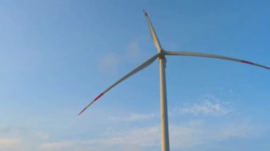 Rüzgar türbini, açık denizlerdeki bir rüzgar tarlasında, güneş doğarken alçak güneşe karşı yakın çekim. Yeşil ve yenilenebilir enerji kavramı.