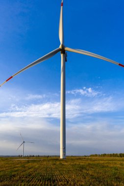 Sabahın köründe rüzgar türbinleri. Alternatif çevre dostu enerji kaynakları. Rüzgar jeneratörü mavi gökyüzüne ve yeşil çimenlere yakın çekim yapıyor.. 