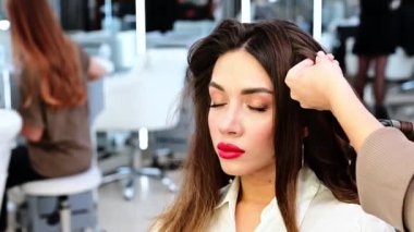 Güzellik salonunda saç şekillendirme için kıvırcık saçlı esmer kadın şefi..