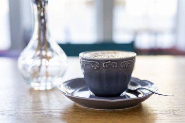 Sabah kahvesi arka planda, güneş ışığının altında..