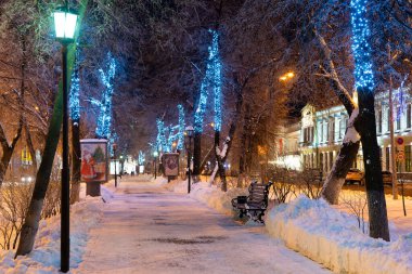 Ulyanovsk, Rusya - 14 Şubat 2022: Yeni Yıl dekorasyonları ve bankları olan kış sokağı. Noel süslemeleri içinde karla kaplı cadde.