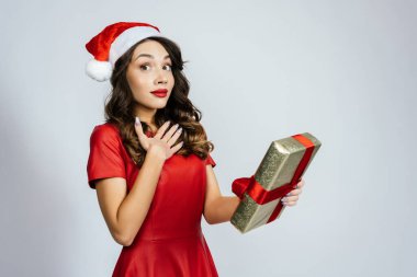 Kadın beklenmedik bir hediye aldı. Beyaz bir arka planı olan Noel şapkalı güzel bir esmer..