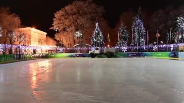 Ulyanovsk, Rusya - 6 Ocak 2022: Bir buz makinası, Noel süslemeleri ve pırıltılı çelenklere karşı buz pateni pistinde yüzeye çıkıyor.