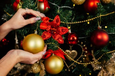 Güzel kadın elleri Noel ağacına yakın çekimde bir Noel topu alır. Noel süslemeleri.