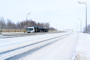 Bir araba taşıyıcı römorku, araba taşıyıcısı, yarı kamyon, traktör ünitesi. Kargo taşımacılığı sert kış koşullarında kaygan, buzlu ve karlı yollarda. 