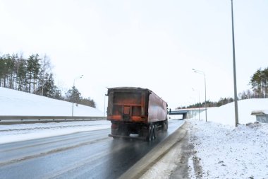 Bir çöp kamyonu, yarı karavan, yarı kamyon, traktör ünitesi ve yük taşımak için yarı karavan. Kargo taşımacılığı sert kış koşullarında kaygan, buzlu ve karlı yollarda.