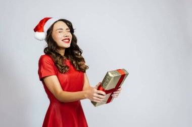 Kadın hayalini kurduğu hediyeyi aldı. Beyaz bir arka planı olan Noel şapkalı güzel bir esmer..