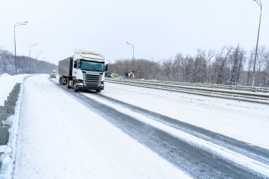 Bir çöp kamyonu, yarı karavan, yarı kamyon, traktör ünitesi ve yük taşımak için yarı karavan. Kargo taşımacılığı sert kış koşullarında kaygan, buzlu ve karlı yollarda.