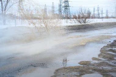 Su basmış bir yoldaki büyük bir su birikintisinin içinden araba geçiyor. Hareket eden araba, tekerleklerden fışkıran su birikintisi..