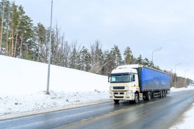 Yarı karavan kamyonu, yarı kamyon, traktör ünitesi ve yük taşımak için yarı karavan. Kargo taşımacılığı sert kış koşullarında kaygan, buzlu ve karlı yollarda.