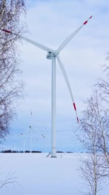 Karlı bir tarlada dondurucu bir kış gününde rüzgâr türbinleri. Şiddetli hava koşullarında alternatif enerji kaynakları. Resimli kış manzarası.