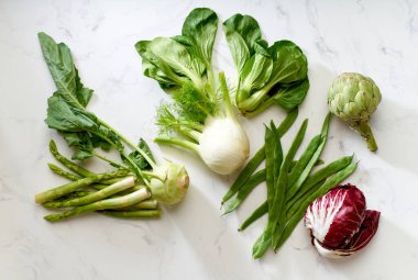 Salata ve sebze kompozisyonu beyaz mermer masa, üst görünüm, sağlıklı vejetaryen gıda konsepti