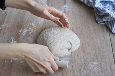 Dişi eller, hamur yoğurmak ve katlamak için mutfak tezgahının üzerinde rustik ekşi ekmek pişirir..