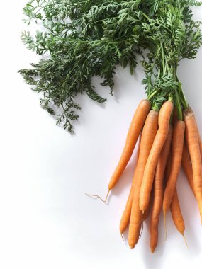 Fresh carrots with greens top view on white background