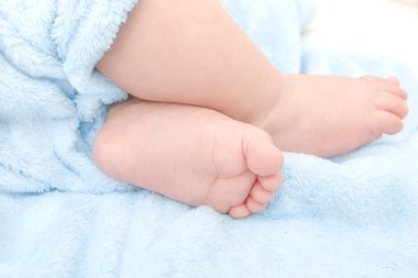 Mavi bir battaniyenin üzerinde sevimli erkek çocuk ayakları.