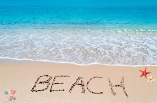 Turquoise foreshore with shells and starfish and "beach" written — Stock Photo, Image