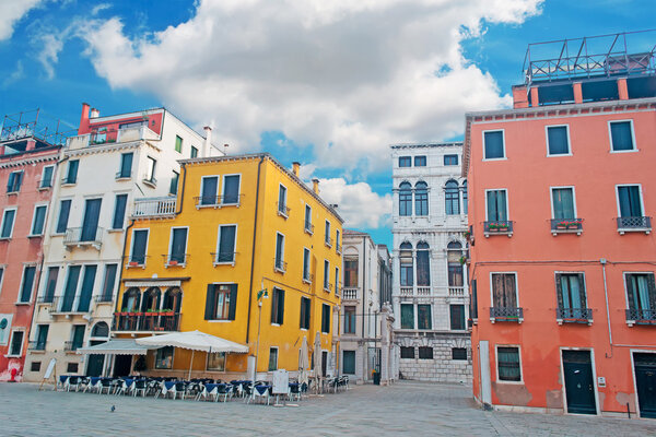 Venetian square with colorful building under a cloudy sky