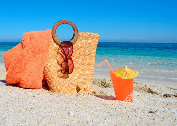 Handdoek, tas en drankje op het zand — Stockfoto