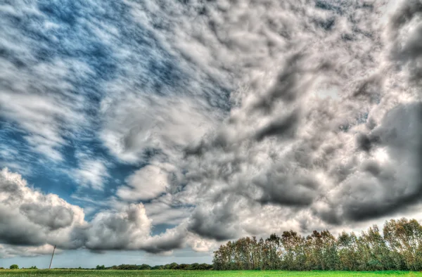 Dramatiska moln över ett fält — Stockfoto