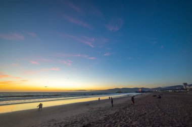 Santa Monica sahilindeki insanlar gün batımında. Kaliforniya, ABD