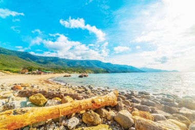 Güneşli bir günde La Speranza sahilinde dalgalar ve kayalar. Sardunya, İtalya