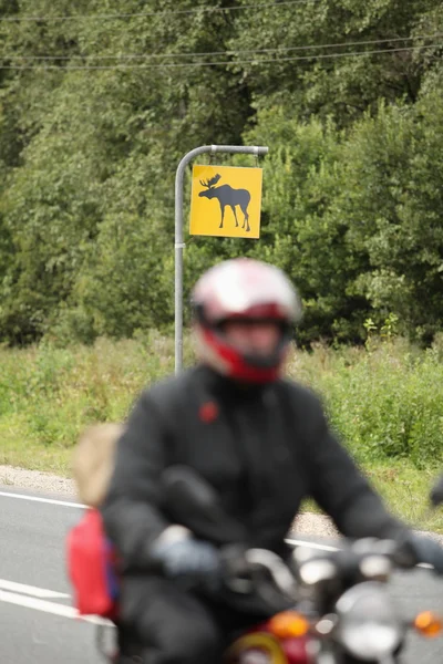 Motorcyclist on a background road sign — Stock Photo, Image