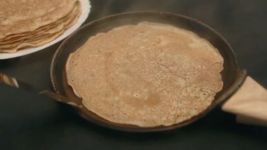 cook bakes pancakes in a pan close-up