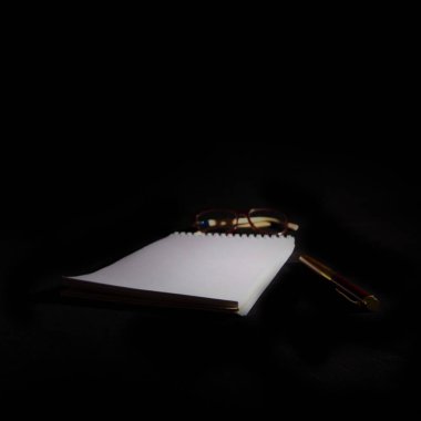 İş yeri ofisi. Not defteri, gözlük ve kalemin yakın görüntüsü. İş ve finans kavramı.