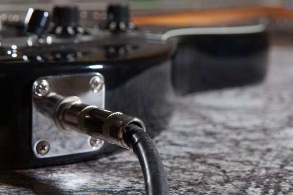 Electric guitar, beautiful, black on a asphalt background. Close-up