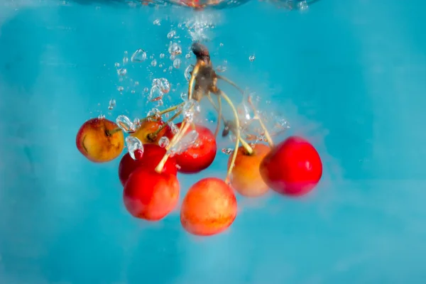 Cerejas salpicando em wate — Fotografia de Stock