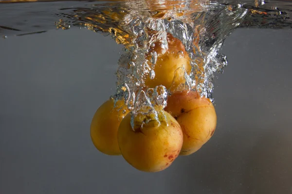 Apricot splashing in water — Stock Photo, Image