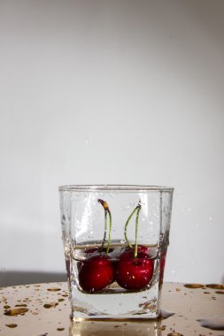 bir bardak su ile bir sıçrama ile kiraz düşüyor.