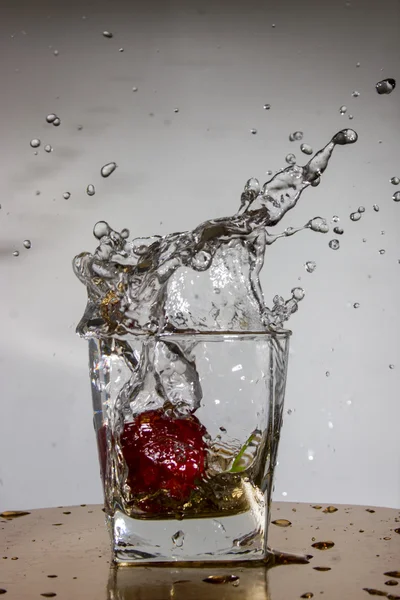 Fresa cae con un chapoteo en un vaso con agua —  Fotos de Stock