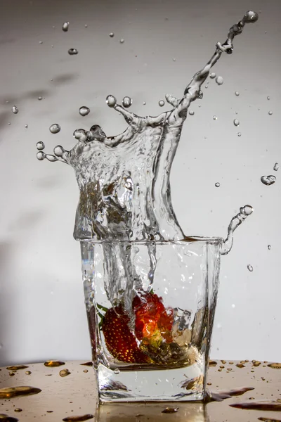 Strawberry falls with a splash in a glass with water — Stock Photo, Image