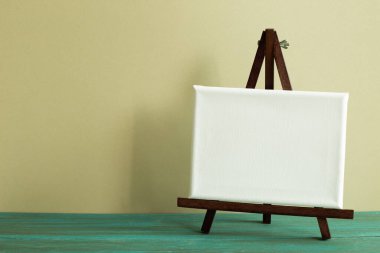 Yeşil ahşap masa üzerinde boş tuval ile Easel. haki duvar arkaplanı