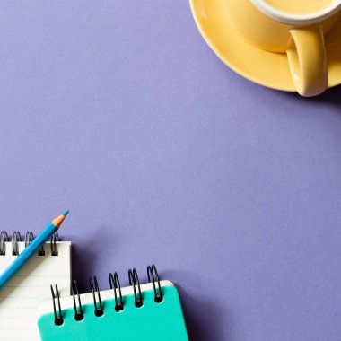 Mor arka planda not defteri ve bardak. düz alan, üst görünüm, kopyala boşluk