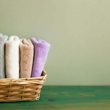 Tahta masadaki havlular sepetin içinde. Yeşil duvar arkaplanı. Boşluğu kopyala