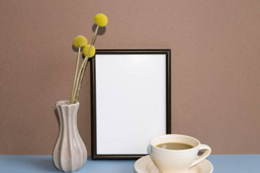 Kuru çiçekli boş resim çerçevesi ve mavi masada bir fincan kahve. Kahverengi duvar arka planı. Boşluğu kopyala