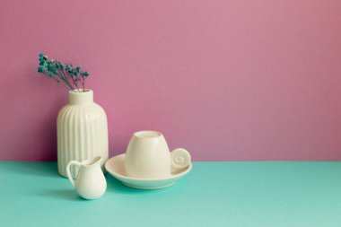 Nane yeşili masada beyaz kahve fincanı ve vazo dolusu kuru çiçek. pembe duvar arkaplanı