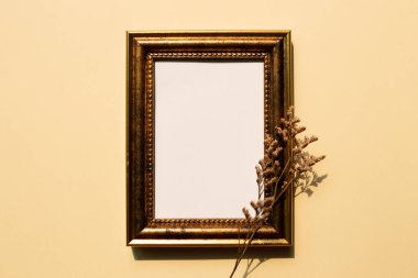 Bej arka planda kuru çiçekli antika altın rengi fotoğraf çerçevesi. Boşluğu kopyala