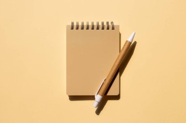 Bej arka planda defter ve kalem. Üst görünüm, boşluk kopyala