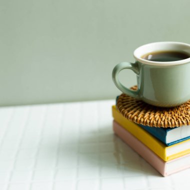 Beyaz masada bir fincan kahve ve defter. haki yeşil duvar arkaplanı