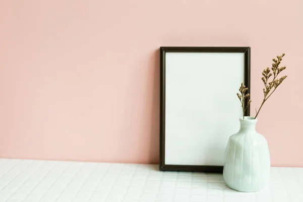 Home interior decor, Picture frame and vase of dry plant on white table. pink wall background