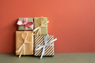 Haki masadaki hediye kutuları. Kırmızı duvar arkaplanı. Yıl dönümü, doğum günü, Noel, selamlama kavramı